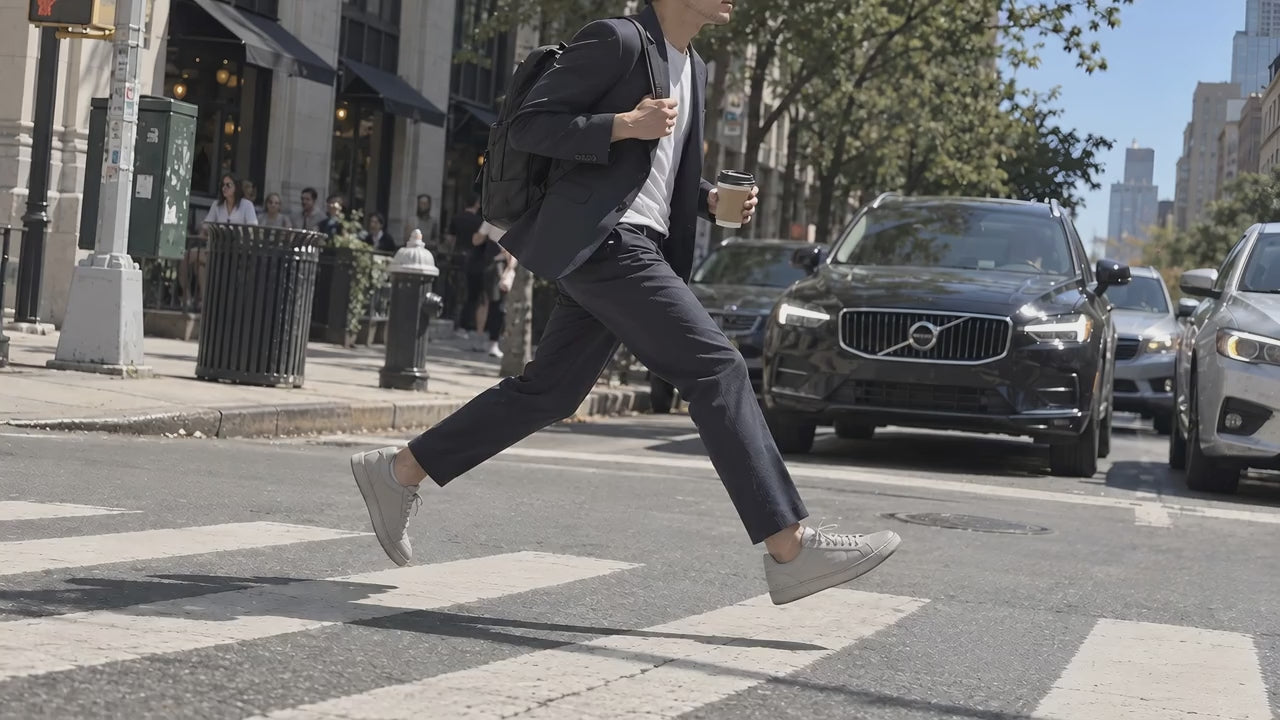 A man in gray TREAD Court sneakers crossing the street