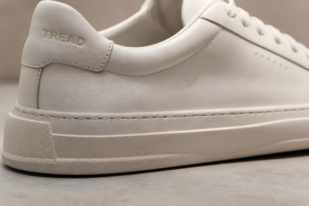 TREAD device macro: the sole edge and stitch line close, embossed TREAD on the heel tab, raking light
