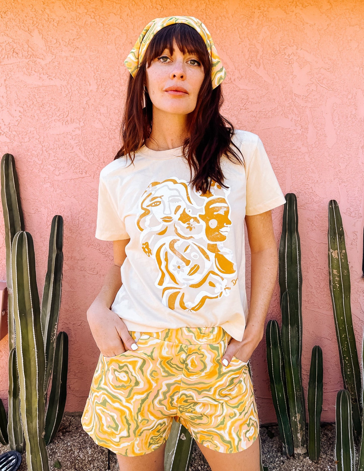 A woman wearing white t-shirt with an orange and white abstract print on, in the shape of faces.