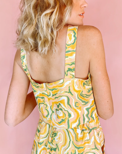 A woman wearing a yellow crop top with a green and orange abstract print on it